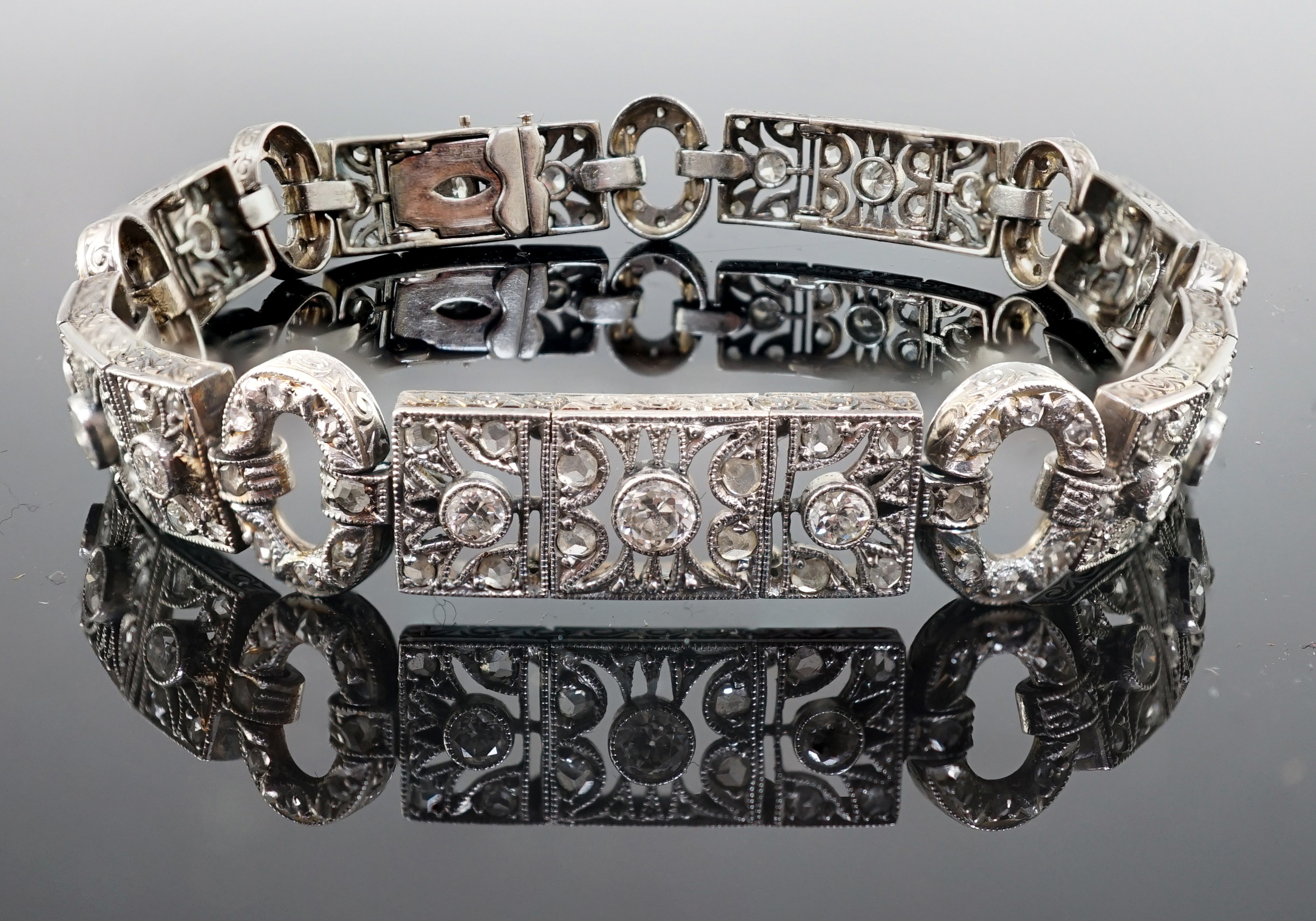 A 1920's pierced 18ct white gold and millegrain set round and rose cut diamond cluster bracelet